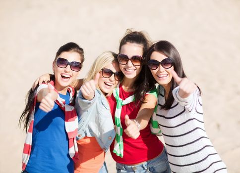 summer, holidays, vacation, happy people concept - beautiful teenage girls or young women showing thumbs up