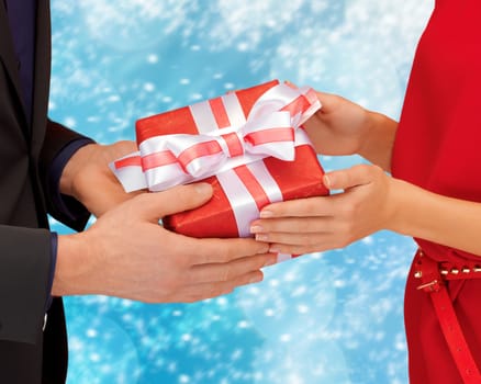 christmas, x-mas, winter, holidays, happiness concept - man and woman hands with gift box