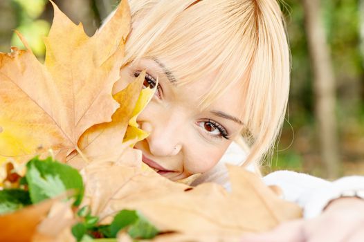 young blonde behind the leaves on summer day
