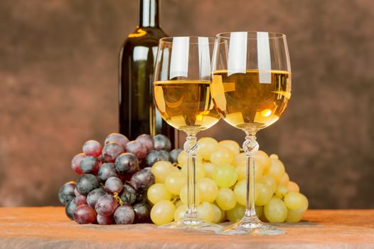 cups of white wine in front of grape and bottle
