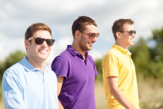 summer, holidays, vacation, happy people concept - group of friends walking on the beach