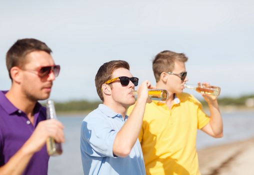 summer, holidays, vacation, happy people concept - group of friends having fun on the beach with bottles of beer or non-alcoholic drinks