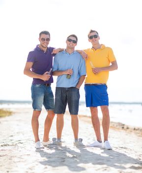 summer, holidays, vacation, happy people concept - group of friends having fun on the beach with bottles of beer or non-alcoholic drinks