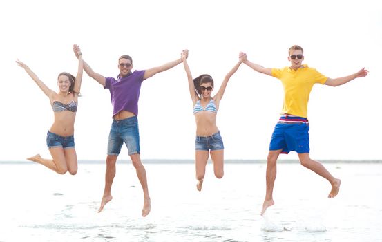 summer, holidays, vacation, happy people concept - group of friends or couples jumping on the beach