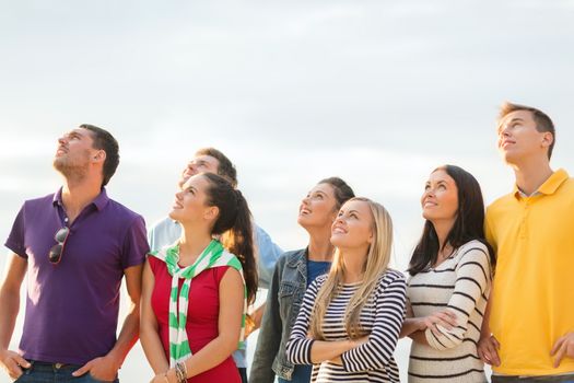 summer, holidays, vacation, happy people concept - group of friends looking up on the beach