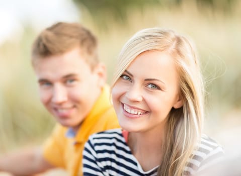 summer, holidays, vacation, happy people and dating concept - couple or friends sitting at the sea side