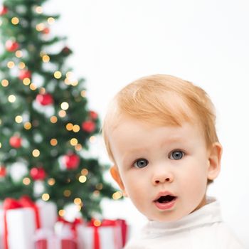 winter, people, x-mas, happiness concept - happy little boy with christmas tree and gifts