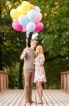 summer holidays, celebration and dating concept - couple with colorful balloons in the park