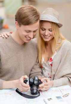 summer holidays and dating concept - couple with photo camera at cafe in the city