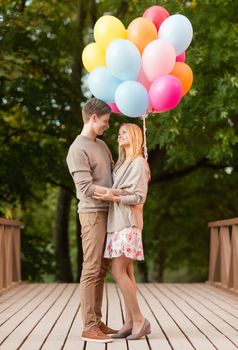 summer holidays, celebration and dating concept - couple with colorful balloons in the park