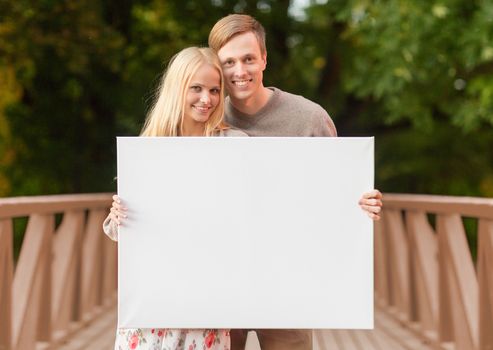 summer holidays, love, travel, tourism, relationship and advertisement concept - romantic couple on the bridge with blank white board