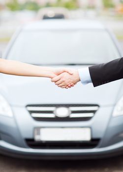 transportation, business, shopping and ownership concept - customer and salesman shaking hands outside