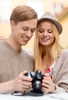summer holidays and dating concept - couple with photo camera at cafe in the city