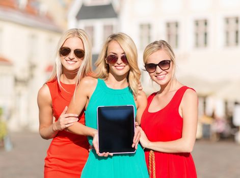 holidays and tourism concept - beautiful blonde girls toursits showing tablet pc with blank screen in the city