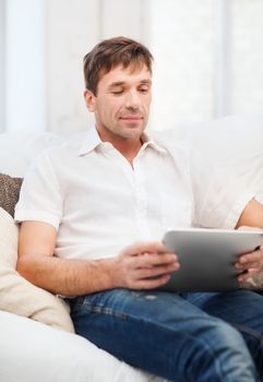 technology and lifestyle concept - handsome man working with tablet pc at home