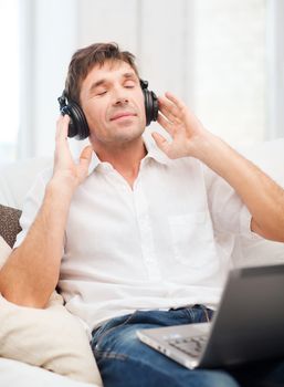 technology, leisure and lifestyle concept - happy man with headphones listening to music at home