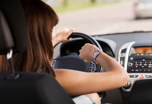 transportation and vehicle concept - woman driving a car and looking at watch