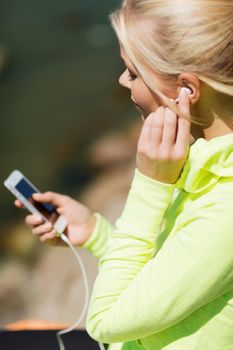 sport and lifestyle concept - woman doing sports and listening to music outdoors