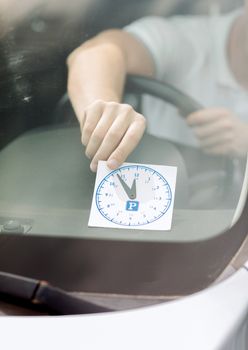 transportation and vehicle concept - man placing parking clock on car dashboard under windscreen