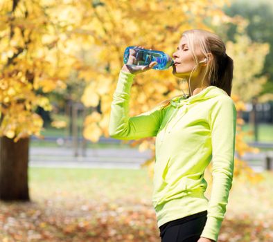 fitness and lifestyle concept - woman drinking water after doing sports outdoors