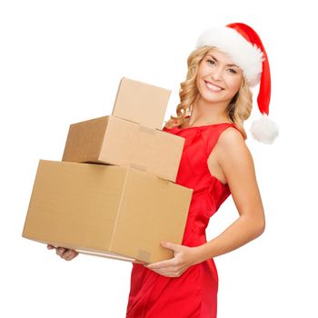christmas, x-mas, winter, happiness concept - smiling blonde woman in santa helper hat with many parcel boxes