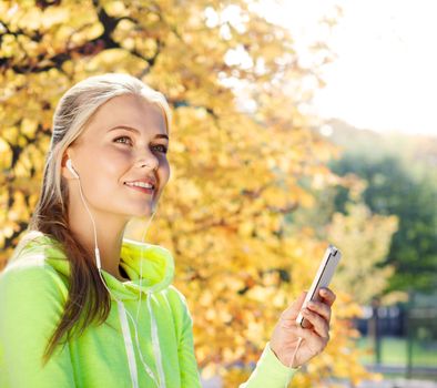 sport and lifestyle concept - woman doing sports and listening to music outdoors