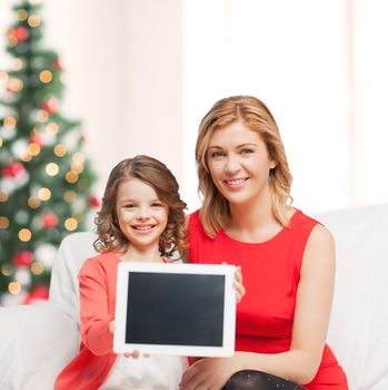 christmas, x-mas, winter, happiness, advertisement, modern technology concept - mother and daughter with tablet pc showing blank screen
