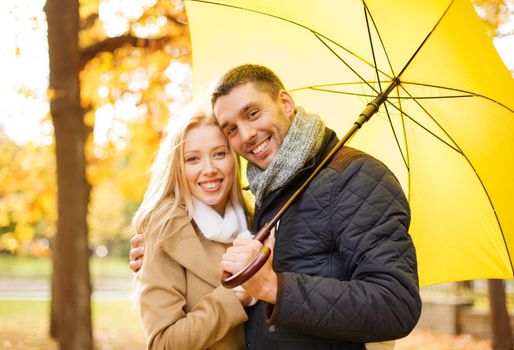 holidays, love, travel, tourism, relationship and dating concept - romantic couple with umbrella in the autumn park