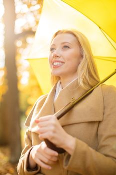 holidays, seasons, travel, tourism, happy people concept - smiling woman with yellow umbrella in the autumn park