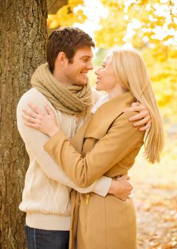 holidays, love, travel, tourism, relationship and dating concept - romantic couple kissing in the autumn park