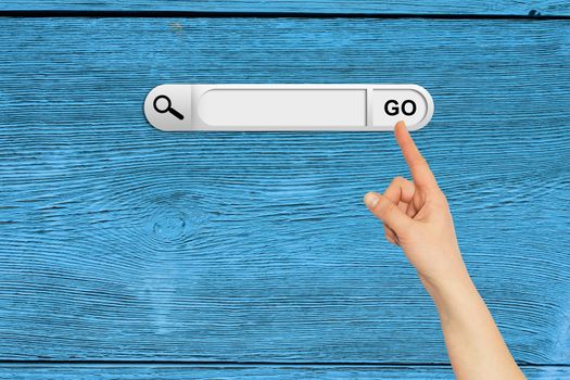 Human hand indicates the search bar in browser. Aged wooden painted surface on background