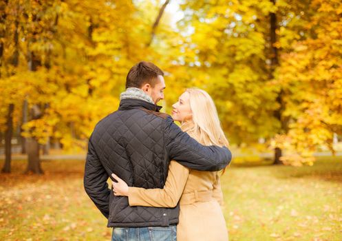 holidays, love, travel, tourism, relationship and dating concept - romantic couple kissing in the autumn park