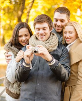 summer, holidays, vacation, travel, tourism, happy people concept - group of friends or couples having fun with photo camera in autumn park