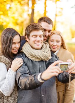 summer, holidays, vacation, travel, tourism, happy people concept - group of friends or couples having fun with photo camera in autumn park