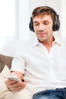 technology, leisure and lifestyle concept - happy man with headphones listening to music at home