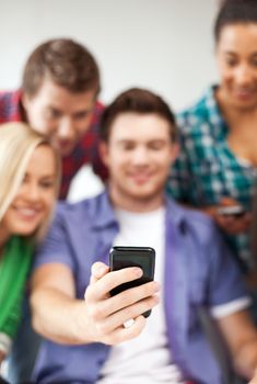 education and internet - smiling students looking at smartphone