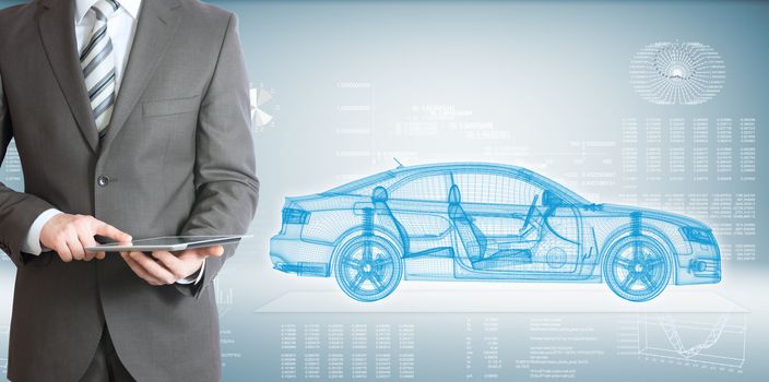 Businessman standing with tablet pc . On background of the high-tech wire frame car and graphs