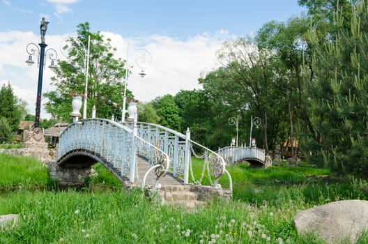 antique style white railing bridge with spectacular park lights in summer time