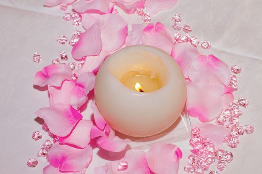 White round candle between petals and jewels