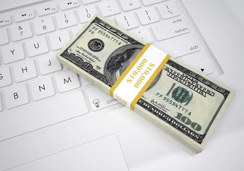 Bundle of dollar bills lying on a computer keyboard. View from above