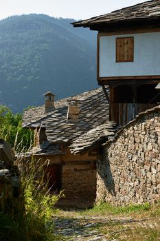 Street with old houses in Kovatchevitsa village, with the Rhodope mountain, Bulgaria