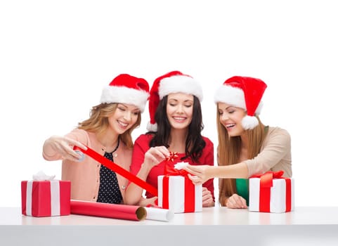 christmas, x-mas, winter, happiness concept - three smiling women in santa helper hats with gift boxes