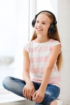 home, leisure, new technology and music concept - little girl with headphones at home