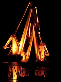 Shipyard cranes by night, multicolored illumination 