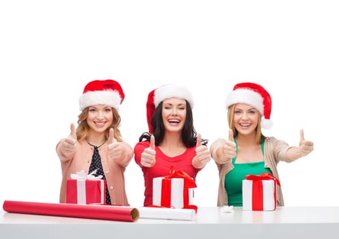 christmas, x-mas, winter, happiness concept - three smiling women in santa helper hats with gift boxes