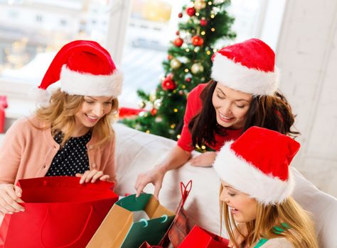 shopping, sale, gifts, christmas, x-mas concept - smiling women in santa helper hats with shopping bags