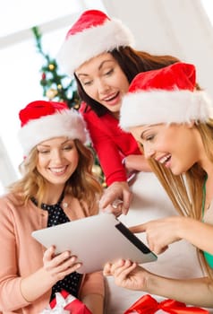 christmas, x-mas, electronics, gadget concept - three smiling women in santa helper hats tablet pc and many gift boxes