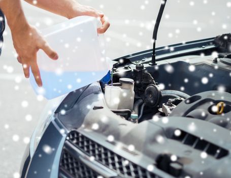 transportation and vehicle concept - man opening car bonnet and filling windscreen water tank with washing liquid