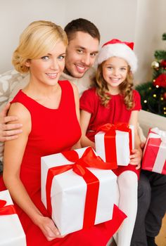 family, christmas, x-mas, winter, happiness and people concept - smiling family in santa helper hats with many gift boxes