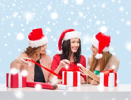 christmas, x-mas, winter, happiness concept - three smiling women in santa helper hats with gift boxes